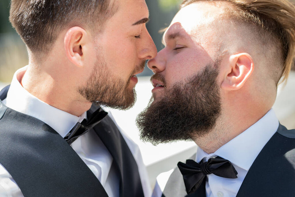 GGay kiss on wedding. Marriage gay couple tender kissing. Close up portrait of gay kissed together during wedding ceremony. Homosexual couple celebrating their wedding. LBGT couple at wedding ceremony - 写真・画像