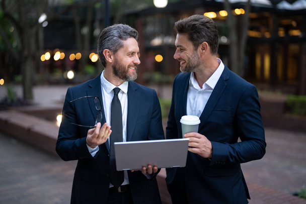 Two happy businessman in suits with laptop, business projects in city. Businessman thinking and plan for business. Managers business man work outside, successful business with technology - Valokuva, kuva