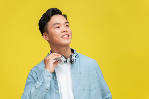 Handsome young man wearing headphones on his neck and smiling  - Foto, afbeelding