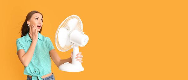 Young woman with electric fan on orange background with space for text - Fotó, kép