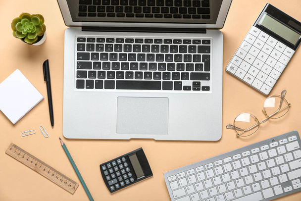 Composition with laptop, calculator and keyboard on beige background - Photo, Image