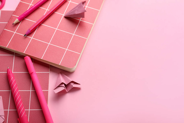 Composition with notebooks, stationery supplies and paper plane on pink background - Foto, imagen