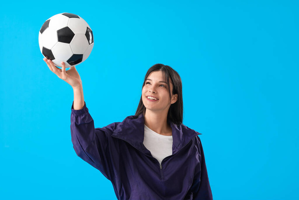 Young woman with soccer ball on blue background - Фото, изображение