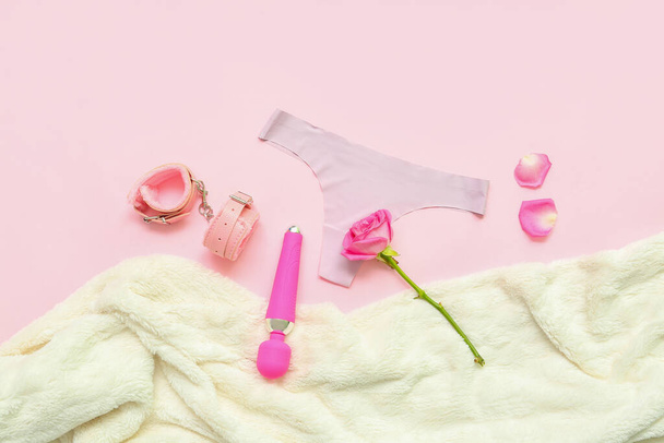 Skład z kobiecych majtek, zabawki seksualne, kwiat róży i kratę na różowym tle - Zdjęcie, obraz