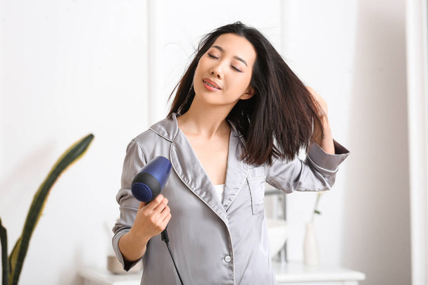 Pretty young Asian woman drying hair in bathroom - Foto, Imagem