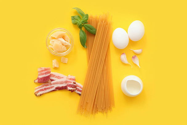 Ingrédients pour savoureuses pâtes carbonara sur fond jaune - Photo, image