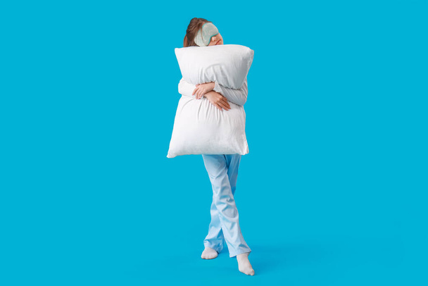 Милая маленькая девочка в маске для сна и подушке на синем фоне - Фото, изображение