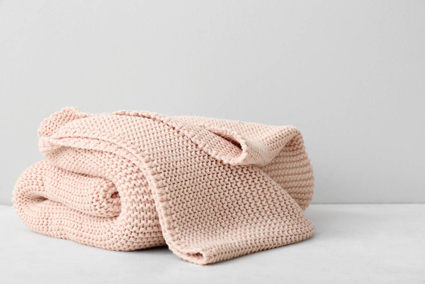 New knitted folded blanket on table near light wall - Photo, Image