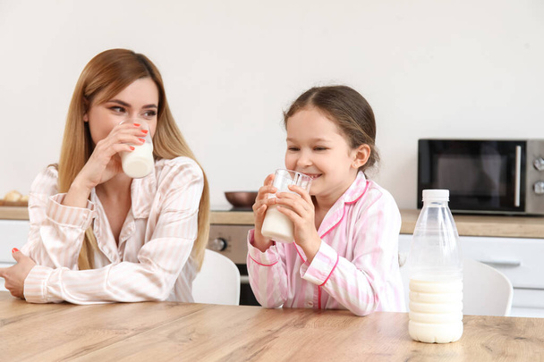 Kleines Mädchen mit ihrer Mutter trinkt Milch in der Küche - Foto, Bild