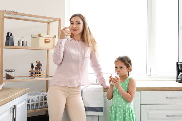 Niña con su madre bebiendo leche en la cocina - Foto, Imagen
