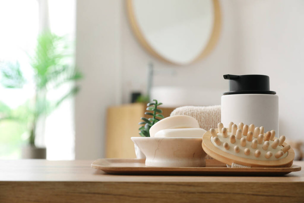 Massagebürste, Seifenspender und Spender auf Holztisch im Badezimmer, Nahaufnahme - Foto, Bild