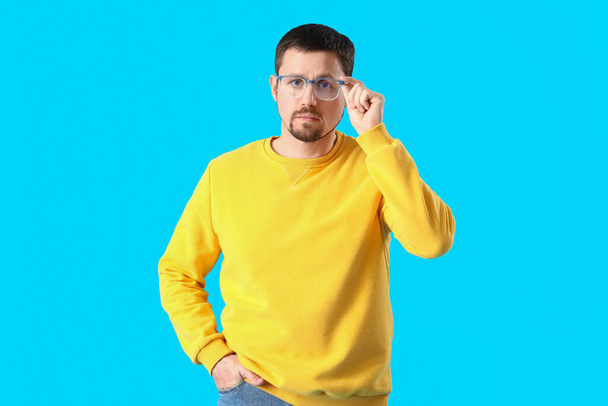Handsome man in stylish eyeglasses on blue background - Zdjęcie, obraz