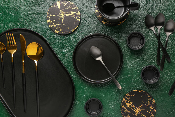 Platos limpios, taza y juego de cubiertos de oro en la mesa grunge verde - Foto, imagen