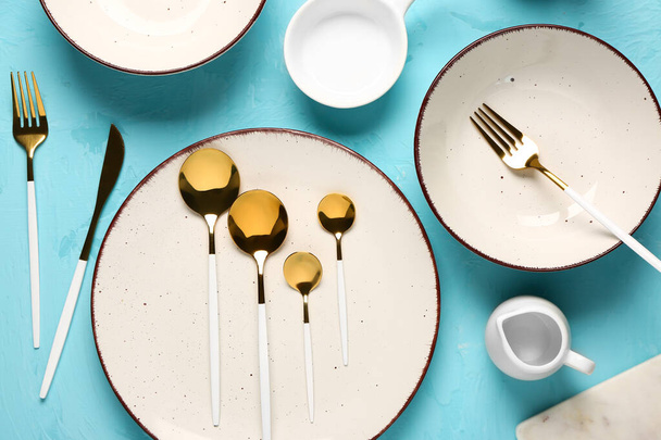 Clean plates and set of golden cutlery on blue grunge table - Photo, Image