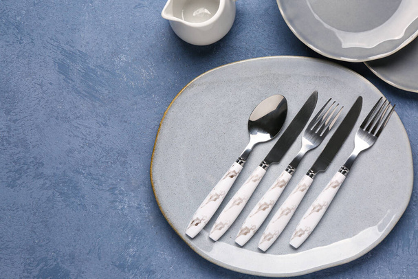 Clean plates with set of cutlery on grey grunge table - Fotoğraf, Görsel