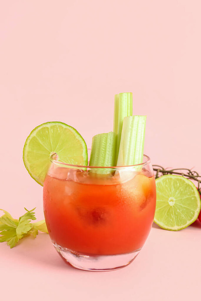 Glass of bloody mary with celery and lime on pink background - Photo, Image