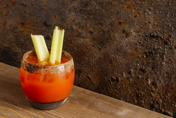 Glass of bloody mary with celery on wooden table - Photo, Image