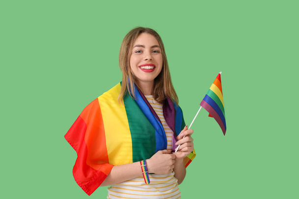 Jonge vrouw met LGBT vlaggen op groene achtergrond - Foto, afbeelding