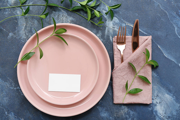 Beautiful table setting with blank invitation card and plant branches on blue table - Foto, Imagem
