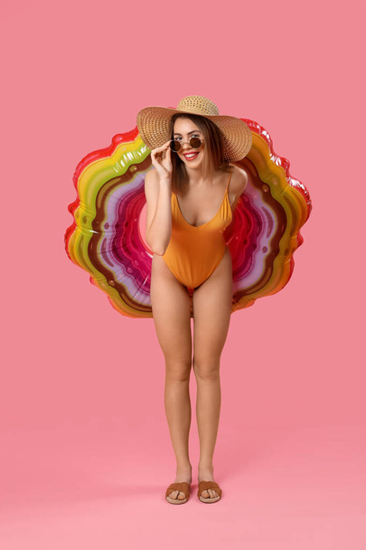 Young woman in swimsuit with inflatable ring on pink background - Φωτογραφία, εικόνα