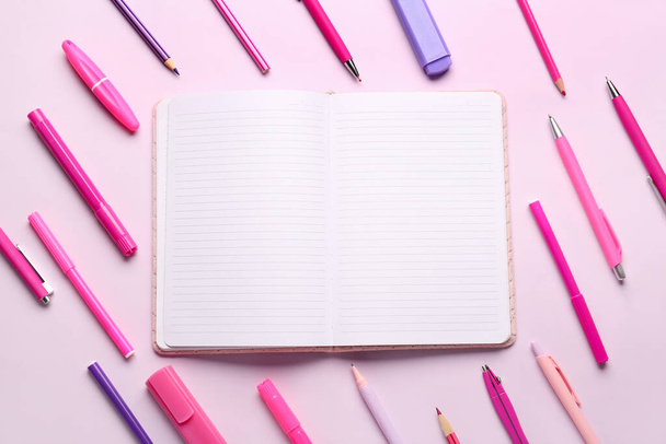 Cuaderno con diferentes artículos de papelería escolar sobre fondo lila - Foto, imagen