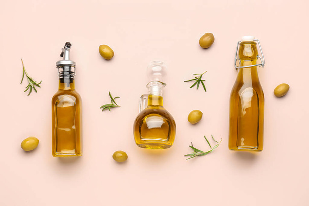 Flaschen und Krug mit Olivenöl auf rosa Hintergrund - Foto, Bild