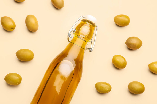 Eine Flasche frisches Olivenöl auf beigem Hintergrund - Foto, Bild
