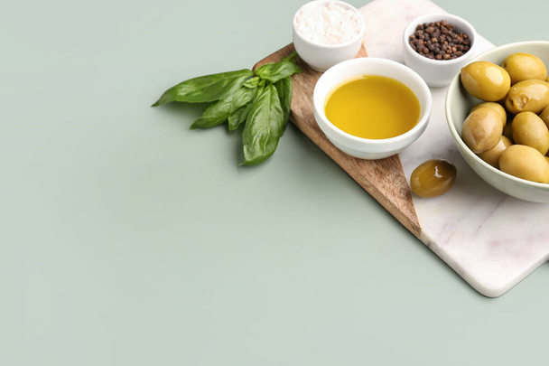 Cuencos con aceitunas maduras y aceite sobre fondo verde - Foto, imagen