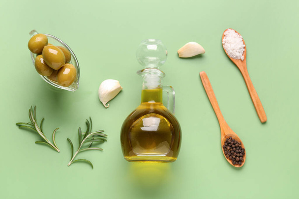 Подливка с созревшими оливками и кувшином масла на зеленом фоне - Фото, изображение
