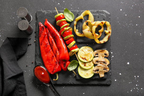 Slate board with tasty grilled vegetables on grunge background - Fotó, kép