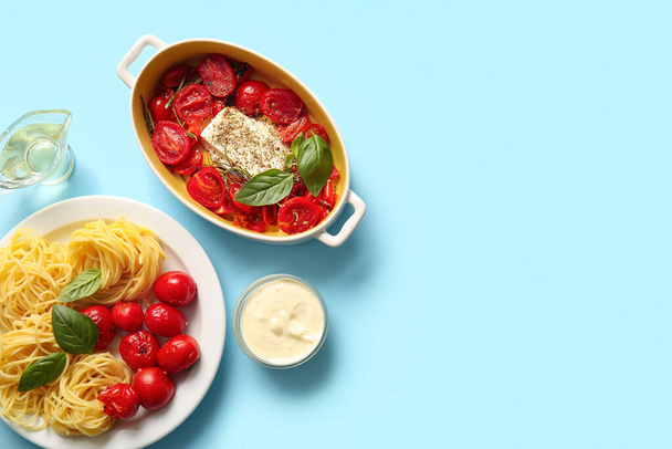 Baking dish with tasty tomatoes, feta cheese and pasta on blue background - Photo, Image