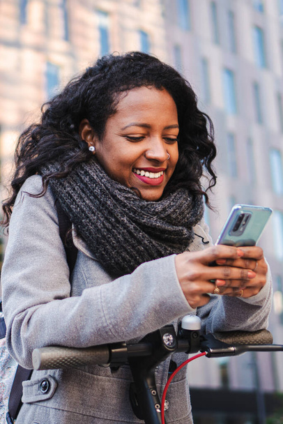 Vertical portrait of business young woman texting and browsing on smartphone at office workplace outside. Smiling cheerful girl having fun and laughing using a cellphone social media app. High quality - Photo, Image