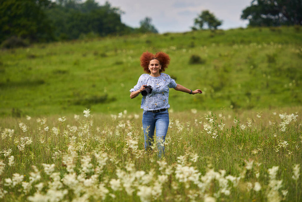 Woman nature photographer happy and cheerful, running with camera on a meadow - Foto, afbeelding