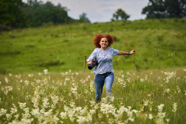 Woman nature photographer happy and cheerful, running with camera on a meadow - Foto, immagini