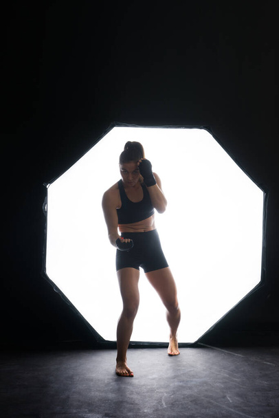 Naisnyrkkeilijä treenaa pimeässä kehässä. Hidasta vauhtia. Siluetti. Nyrkkeily käsite - Valokuva, kuva