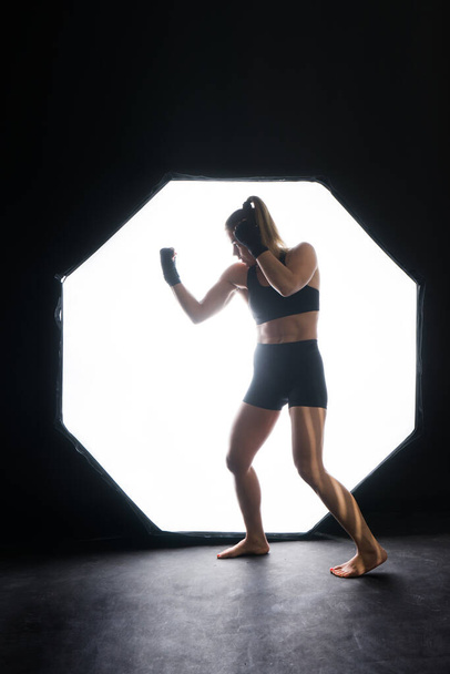 Female boxer training in a dark ring. Slow motion. Silhouette. Boxing concept - Photo, Image