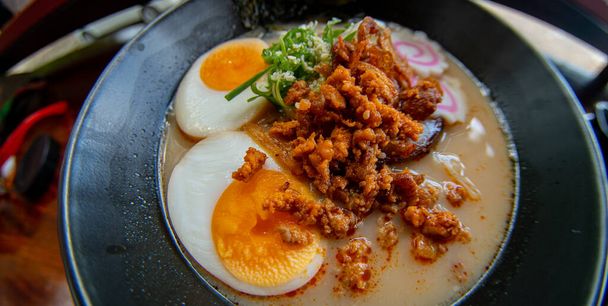 Ράμεν μπολ με νούντλς, χοιρινό, κοτόπουλο, βραστό αυγό και λαχανικά σερβιρισμένα με σαλάτα φυκιών - Φωτογραφία, εικόνα