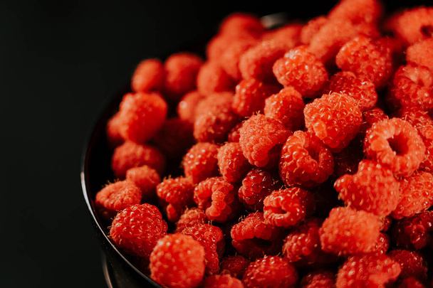 Fresh, ripe, juicy raspberry background, close up berry . Food background. Gastronomy concept, organic food. Macro red raspberries fruit in plate on black background - Zdjęcie, obraz