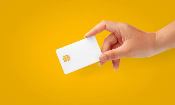 Woman Hand holding  blank credit chip card on a Yellow background for business and finance - Valokuva, kuva