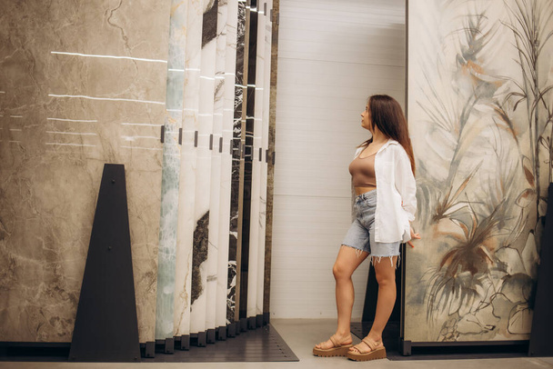 A woman chooses a ceramic tile in a store. - Фото, изображение