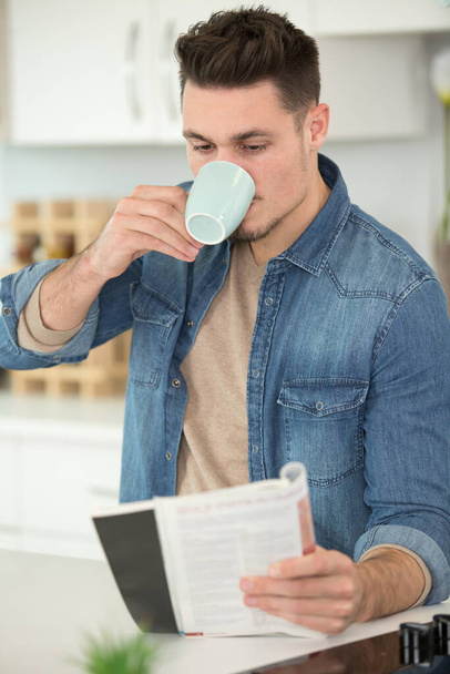 young man drinking a coffee and reading a book - Foto, Imagen