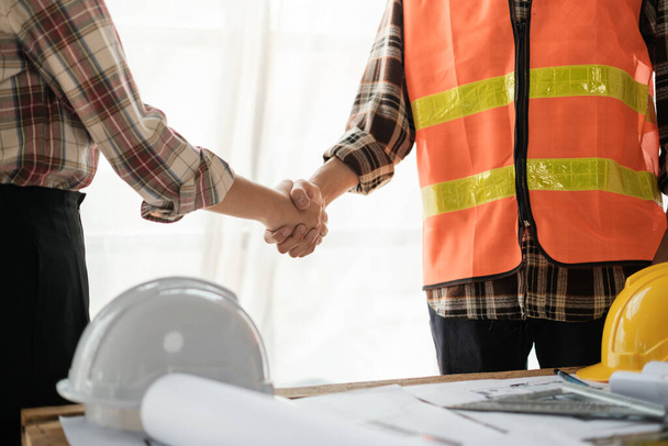 Close-up image of an engineer shaking hands with his coworker during the meeting. teamwork, building trust, unity. High quality photo - Foto, afbeelding