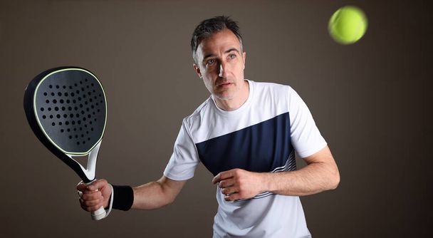 Detail of padel player receiving a ball with sports equipment and isolated dark background. Front view. - Foto, immagini
