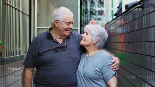 Šťastný starší pár, usmívající se před kamerou, jak stojí v neformální rezidenci venku. Starší manžel a manželka ve stáří portrét - Záběry, video