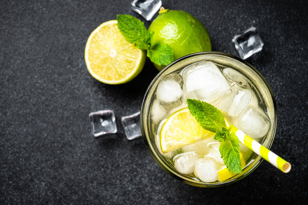 Mojito with rum, lime, mint and ice on black background with bar utensils. Flat lay with copy space. - Fotoğraf, Görsel