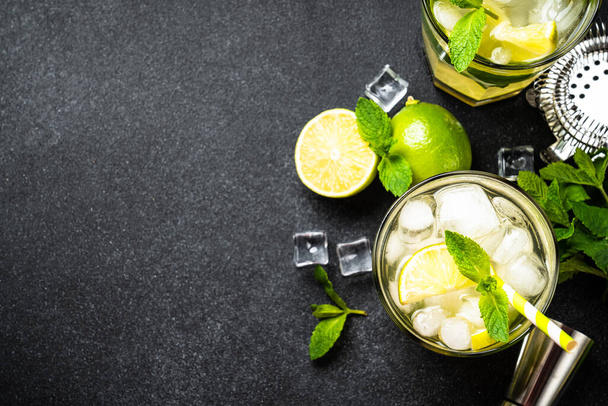 Mojito com rum, limão, hortelã e gelo sobre fundo preto. Tradição Bebida de verão. Depósito plano. - Foto, Imagem