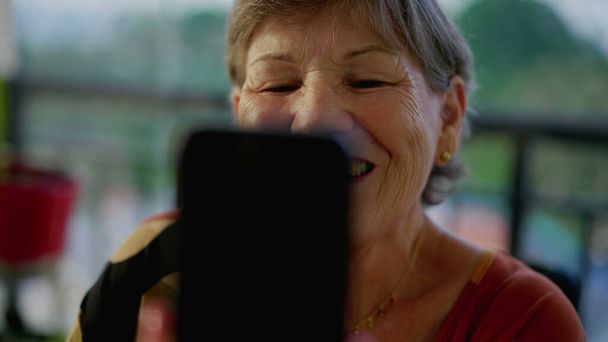 Alegre escena de conexión de video de la abuela mayor hablando con un miembro de la familia a través del teléfono celular y la pantalla técnica - Foto, Imagen
