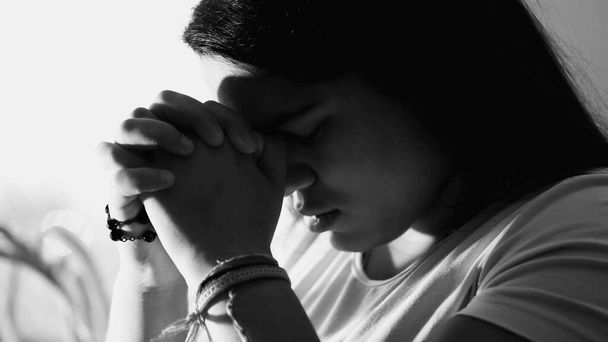 Dramática devoción de la joven rezando a Dios en blanco y negro monocromo. Chica adulta contemplativa espiritual en los años 20 - Foto, imagen