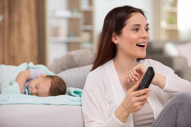 mother watches tv while her baby sleeps - Photo, image
