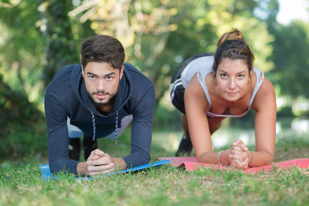 sporty woman and man doing plank in a park - Foto, afbeelding